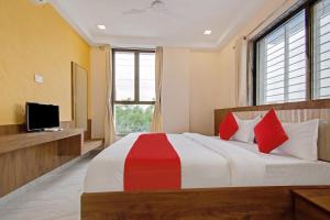 1 dormitorio con 1 cama grande con almohadas rojas en Super Capital O Hotel C Tara, en Shirdi
