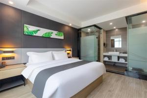 a bedroom with a large white bed and a bathroom at Thank Inn Chain Hotel Guangdong Qingyuan Fogang County 106 National Road in Qingyuan