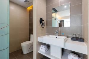 a bathroom with a sink and a toilet and a mirror at Thank Inn Chain Hotel Guangdong Qingyuan Fogang County 106 National Road in Qingyuan