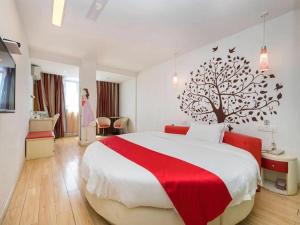 a bedroom with a large bed with a tree on the wall at Thank Inn Chain Hotel Gansu Tianshui Taian Bus Station in Tianshui