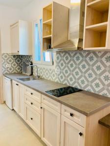 a kitchen with white cabinets and a tile wall at sun studios in Mýkonos City