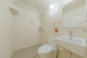 La salle de bains blanche est pourvue de toilettes et d'un lavabo. dans l'établissement Thank Inn Chain Hotel Lanshan District Yitang, à Linyi