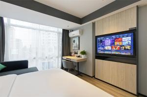 a bedroom with a bed and a desk and a television at Thank Inn Chain Hotel Shanxi Yangquan Yu County West Xiushui Street in Yu