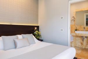 a bedroom with a large white bed and a mirror at Hotel Michelangelo in Carrara