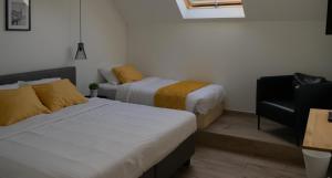 a room with two beds and a chair in it at Au Petit Canteleu - Bed & Breakfast in Beloeil +5 photos