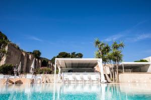 a large swimming pool with chairs and a building at Cave Bianche Hotel in Favignana