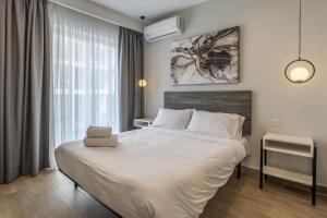 a bedroom with a large white bed and a window at Studio room 11 with kitchenette in the heart of St Julians in Paceville