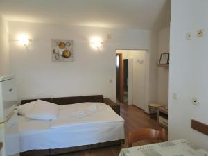 een slaapkamer met een wit bed en een tafel en stoelen bij Apartments Dajana Silo in Šilo