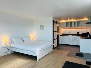 1 dormitorio con 1 cama blanca y cocina en Waterfront Fjord House, en Litli-Árskógssandur