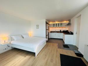 1 Schlafzimmer mit einem weißen Bett und einer Küche in der Unterkunft Waterfront Fjord House in Litli-Árskógssandur