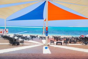 馬特魯港的住宿－Triumph White Sands Hotel，海滩上的一组椅子和一把遮阳伞