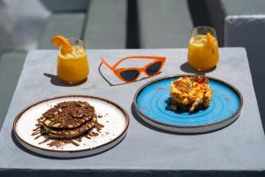 a table with two plates of food and two glasses of orange juice at Twenty One Suites in Oia