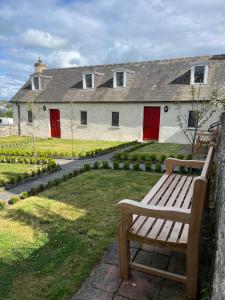 a wooden bench in front of a house with red doors at Alms Houses in Kinsale