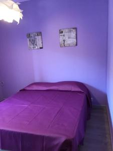 un letto viola in una stanza con due immagini sul muro di Trilocale IMMinens mari a Copanello