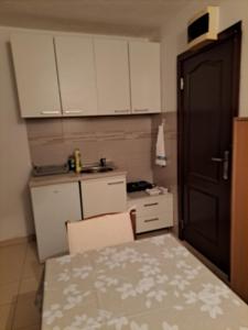 a small kitchen with white cabinets and a table at Ana apartman in Bar