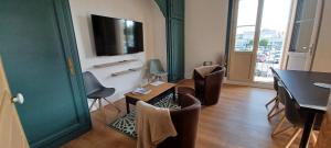 een woonkamer met een tafel en stoelen en een televisie bij Le Logis de la Place in Thouars