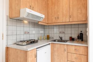 a kitchen with wooden cabinets and a sink and a microwave at Vaso studios in town with parking in Naxos Chora