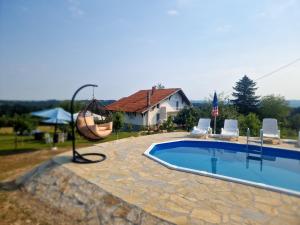 a swimming pool with chairs and a swing and a house at Odmor na selu Babajić in Ljig