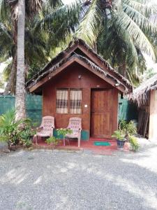 une petite maison avec 2 chaises et une terrasse couverte dans l'établissement Blue Ocean Cabana, à Trincomalee