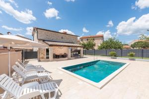 eine Villa mit einem Pool und Liegestühlen in der Unterkunft Villa Maria Tadini in Kaštelir