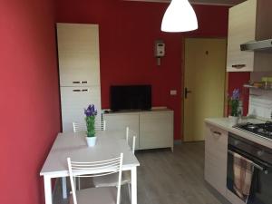 una cucina con tavolo e sedie bianchi e pareti rosse di Bilo Copanello Imminens Mari a Copanello