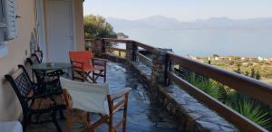 a balcony with chairs and a table and a view of the water at Margherita's holidays home in Agios Spiridon Fokidas