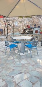 a picnic table and two blue chairs in front of a stone wall at Margherita's holidays home in Agios Spiridon Fokidas