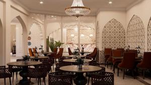 a restaurant with tables and chairs and a chandelier at Reikartz Sote Tashkent in Tashkent