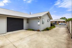 a house with a garage with a driveway at An elegant 2-bedroom house in Hamilton central. in Hamilton