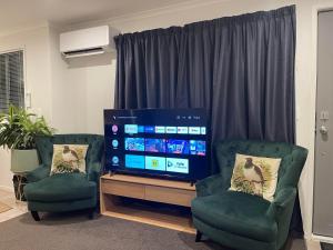 een woonkamer met 2 stoelen en een flatscreen-tv bij An elegant 2-bedroom house in Hamilton central. in Hamilton