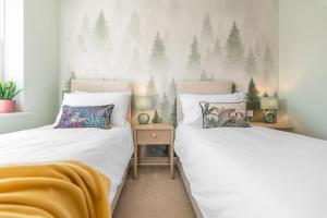 two beds in a bedroom with trees on the wall at #034 Saunders Rest in Norwich