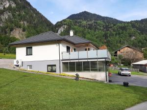 een wit huis voor een berg bij Ferienwohnung Ulrike in Sankt Anton im Montafon