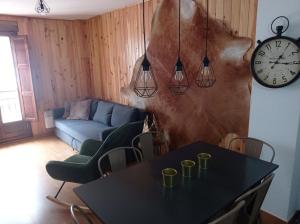 a living room with a table and a clock on the wall at Apartamento Albareda in Canfranc