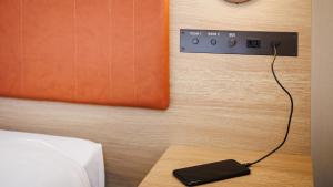 a cell phone plugged into an electrical outlet on a wall at JR-East Hotel Mets Koenji in Tokyo
