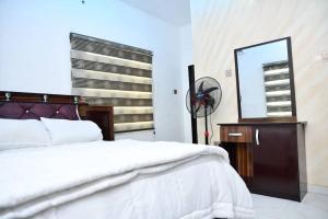 a bedroom with a bed and a mirror and a dresser at Domi Smart 2 Bedroom Serviced Apartment with 24 hour Power in Benin City