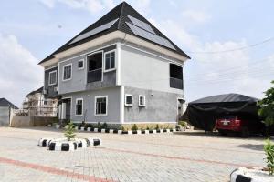 un grand bâtiment blanc avec un toit noir dans l'établissement Domi Smart 2 Bedroom Serviced Apartment with 24 hour Power, à Benin City