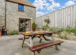 una mesa de picnic de madera frente a un edificio de piedra en Tawny cottage w pool and enclosed garden en Pickering
