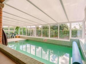 una piscina cubierta con una habitación grande con ventanas en Tawny cottage w pool and enclosed garden en Pickering