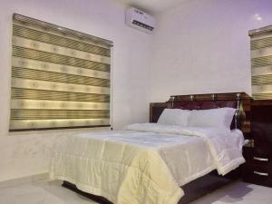 a bedroom with a bed and a large window at Domi Smart 2 Bedroom Serviced Apartment with 24 hour Power in Benin City