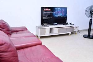 貝寧城的住宿－Domi Smart 2 Bedroom Serviced Apartment with 24 hour Power，客厅配有2张红色沙发和1台平面电视