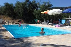 a woman in a swimming pool with an umbrella at Holiday Home Matthäus am Corfutrail, Ferienoase im Olivenhain 3 km zum Meer in Giannádes