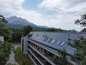 a building with a roof with mountains in the background at TATRYSTAY Luxury Penthouse Apartment PodLesom in Vysoke Tatry - Dolny Smokovec