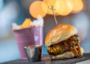 a sandwich on a table with a cup of fries at Peninsula All Suite Hotel by Dream Resorts in Cape Town