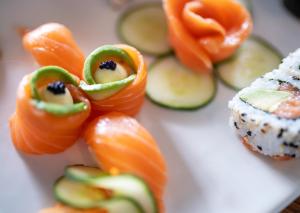 a white plate with sushi and vegetables on it at Peninsula All Suite Hotel by Dream Resorts in Cape Town