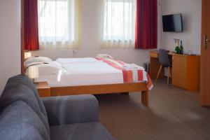um quarto de hotel com uma cama e uma cadeira em Fordan Hotel Pécs em Pécs