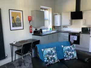 a kitchen with a couch and a table in a kitchen at Jeffersons Abbey Road Serviced Apartments in Barrow in Furness