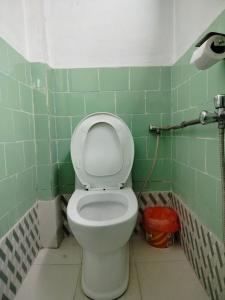 a bathroom with a toilet in a green tiled room at COMMUNITY HOLIDAY INN in Panauti