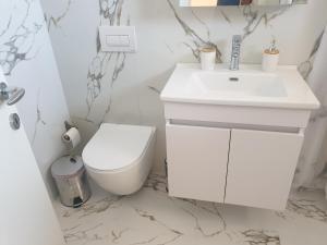 een badkamer met een witte wastafel en een toilet bij Rooms by George in Dhërmi