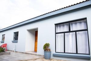 a white house with a window and a red chair at Asania Guest House in Bloemfontein
