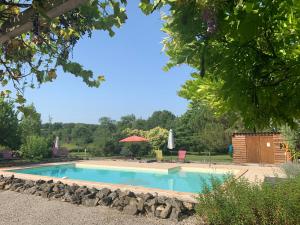 una piscina con tavolo, sedie e alberi di Coutillard a Parisot